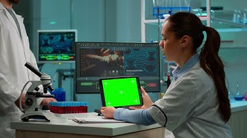 Scientist fiddling with tablet with green screen  - Chroma Key - No Copyright