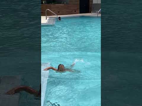 Забавная малышка Наоми плавает в бассейне