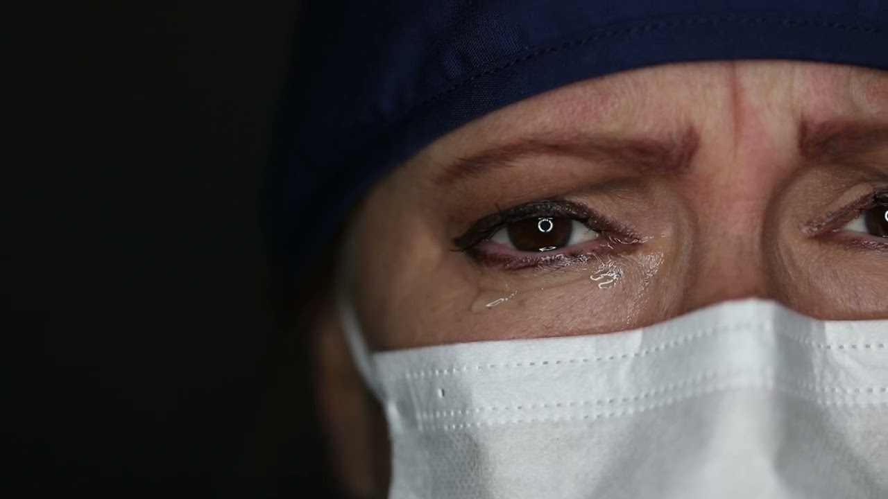 Dramatic Close-up of Lamenting Nurse or Doctor Wearing Face Mask with Tears In Her Eyes.