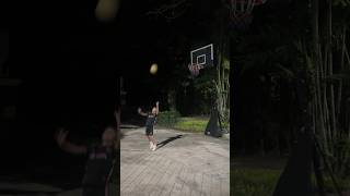 Андрей закидывает мяч в баскетбольное кольцо со спины.