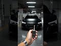 Matte black Audi R8, black carbon smart key, hand holding key near lens, car standing front view, ci