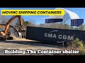 Moving full shipping containers around with a Trackhoe Excavator.  Building the container shelter