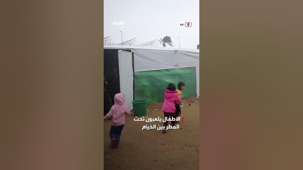 أطفال غزيون فرحون يلعبون تحت المطر بين الخيام بدير البلح
