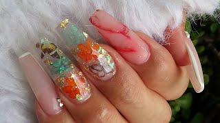 Uñas con naturaleza muerta y mariposas encapsuladas