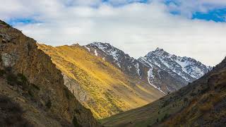 Time-lapse of clouds flying above springtime mountain landscape