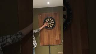 Guy throws dart at board and hits friend on hard