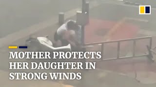 Mother uses body to protect daughter in strong winds in China