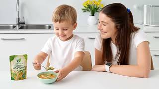Cocina moderna y luminosa, mamá influencer sentada en mesa con hijo pequeño, mamá sirve sopa saludab