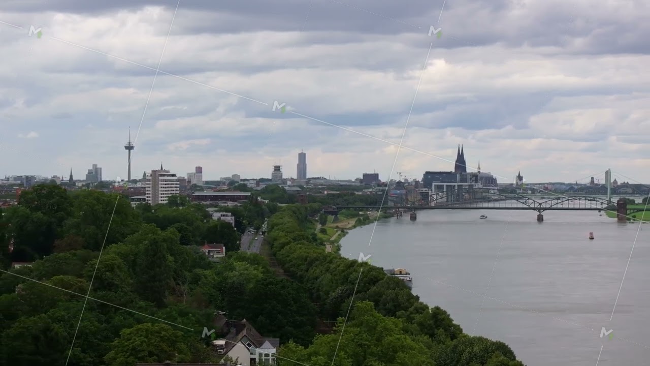 Panoramic view captures Cologne's skyline, featuring the Rhine River and Hohenzollern Bridge, framed