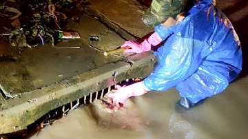 Removal Plastic And Trash Flow With Rain Water Clogged Culvert Drain On Street Road On The Night