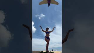 Airplane Lands Over Beach as Girl Poses