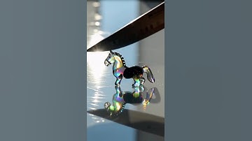 Iridescent obsidian shaped like a chess knight sliced cleanly in half