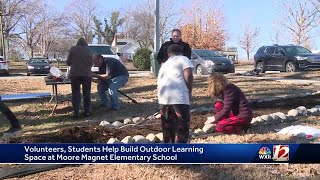 Students and volunteer help build an outdoor learning space