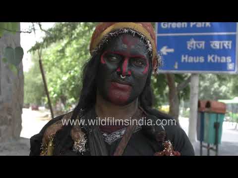 Beggars in black face paint and ornate clothing ask commuters for alms in Hauz Khas
