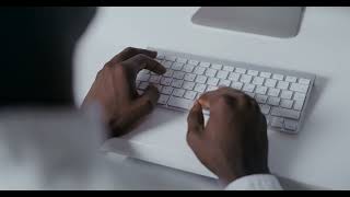 Hands typing on Apple keyboard in a modern office setup.