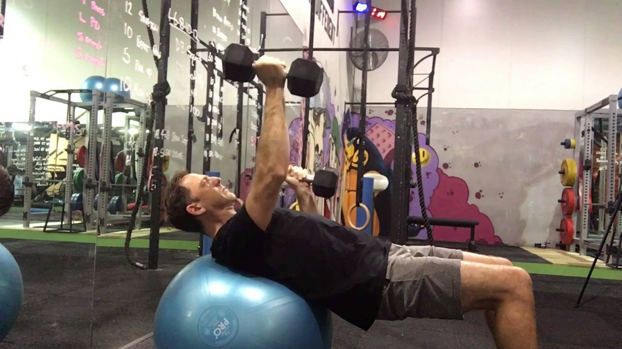 Swiss ball dumbbell alt press spartan logo