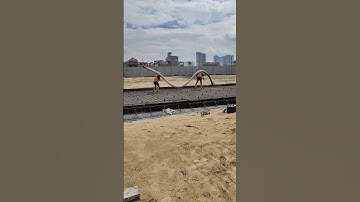 2 workers lift PVC pipe to casting road concrete