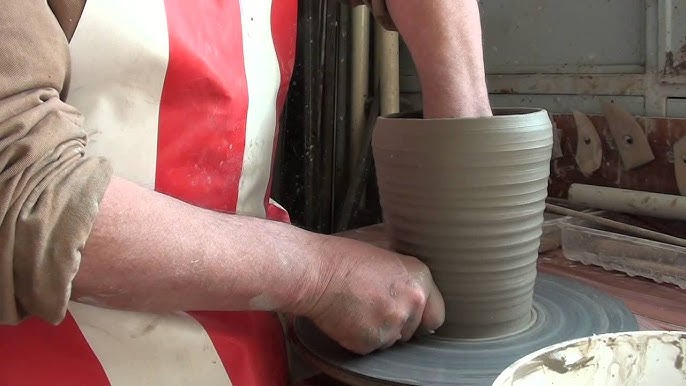Un tornio del vasaio gira con argilla mentre l'artista utilizza le sue mani  bagnate a dar forma ad un vaso in ceramica che verrà successivamente cotto  in un forno per indurire la