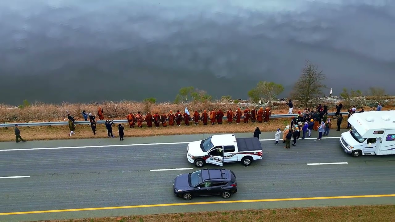 Aerial Zoom Out from Walk for Peace monks on Highway 64 at guardrail at edge of Jordan Lake - 1.23