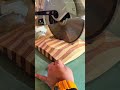 cutting a patterned square wooden block with a large rotating blade using a miter saw machine