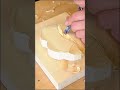 carving a round block of wood meticulously using a sharp metal chisel tool inside a carpentry