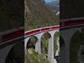 🚂 Breathtaking Aerial Journey: Red Train Cruising Through Lush Mountain Scenery 🏞️