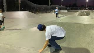 Skateboarder jumps ramp at skatepark and crashes into little boy on scooter