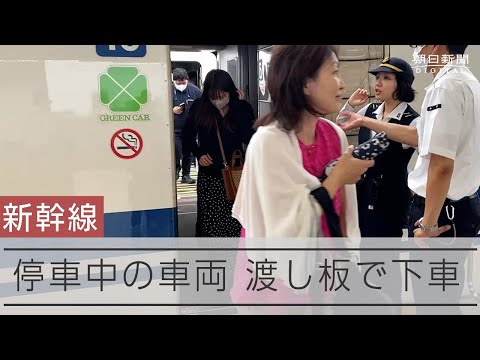 台風７号の影響で停車中の新幹線から三島駅に降りる乗客