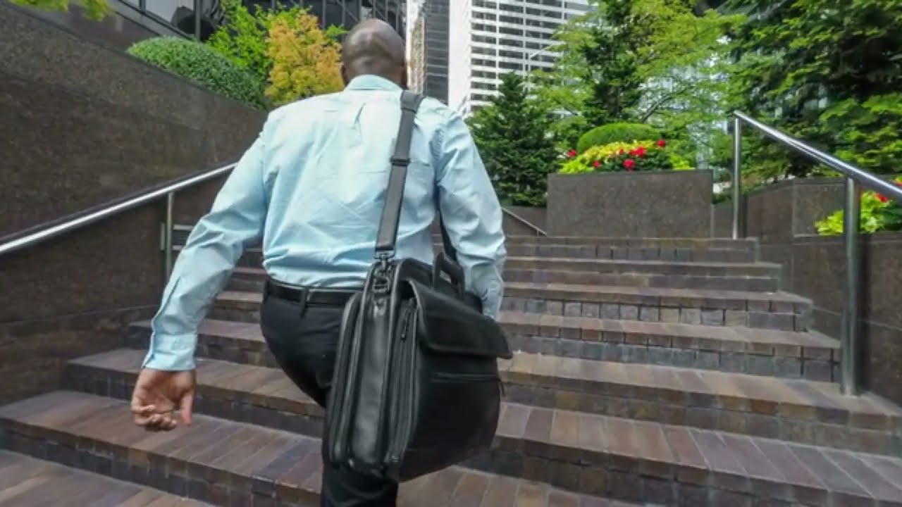 businessman walking to work climbing steps in front of office building