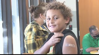 COVID Vaccine clinic in elementary school has students proudly showing off their bandaids