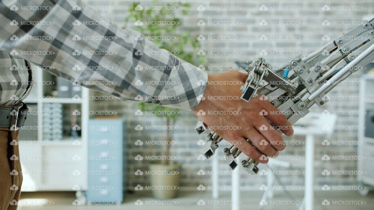 Close-up shot of man and intelligent robot shaking hands in office room