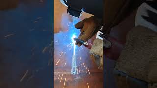 Vertical 3G FCAW pass on heavy structural plate under AWS D1.1 codes.