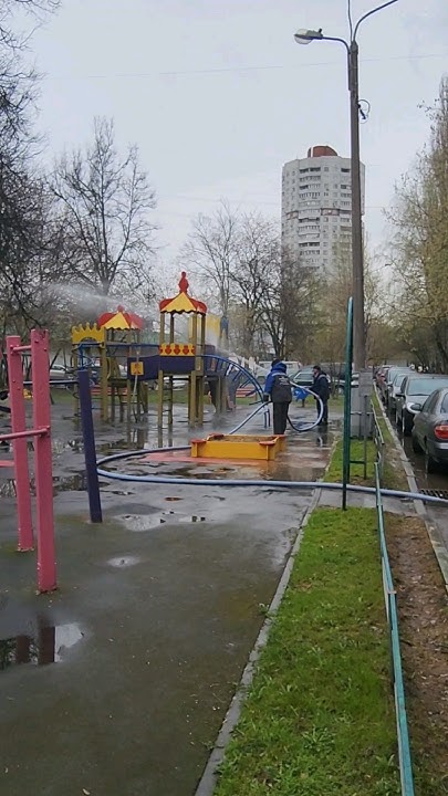 моют детскую площадку из шлангов под напором воды из трактора синего.в ...