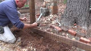 Installing an inexpensive wire fence on a sloped garden landscape