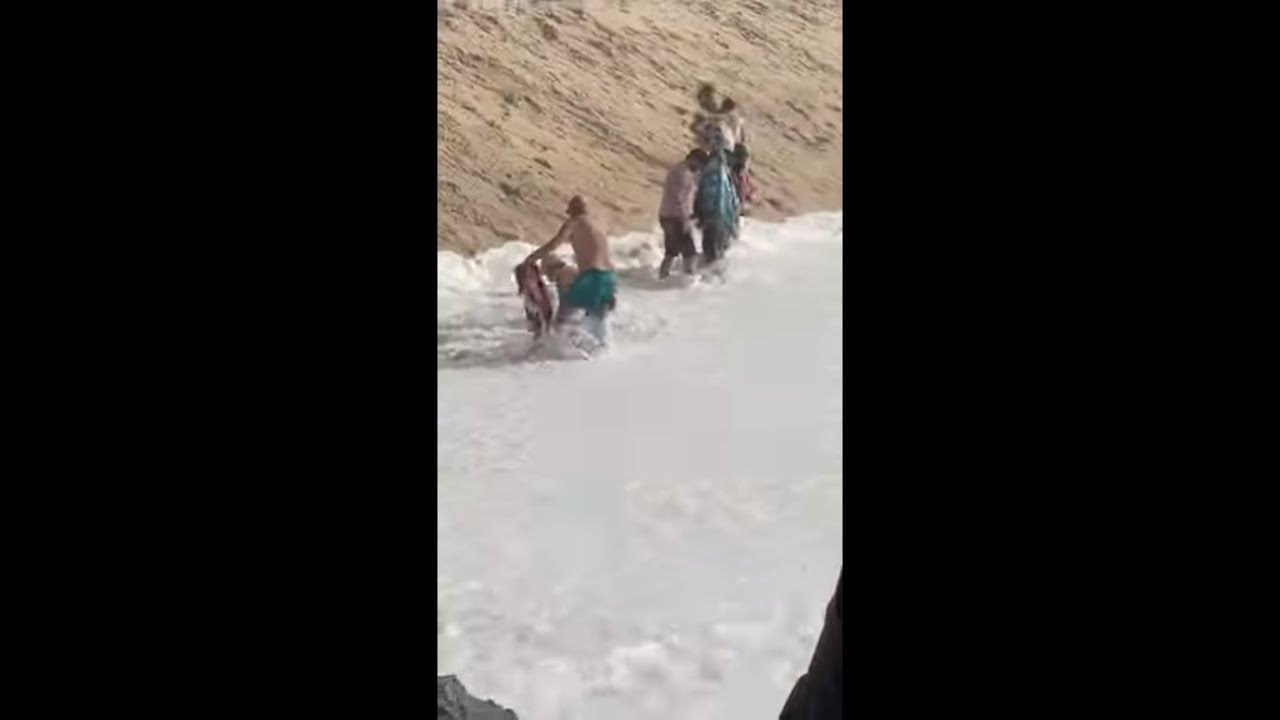 Wave Hits People Laying on Shore Then Washes off a Shoe