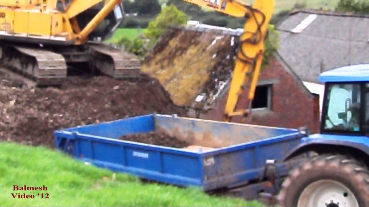 JCB JS130 Excavator loads New Holland TM 140 and Trailer.