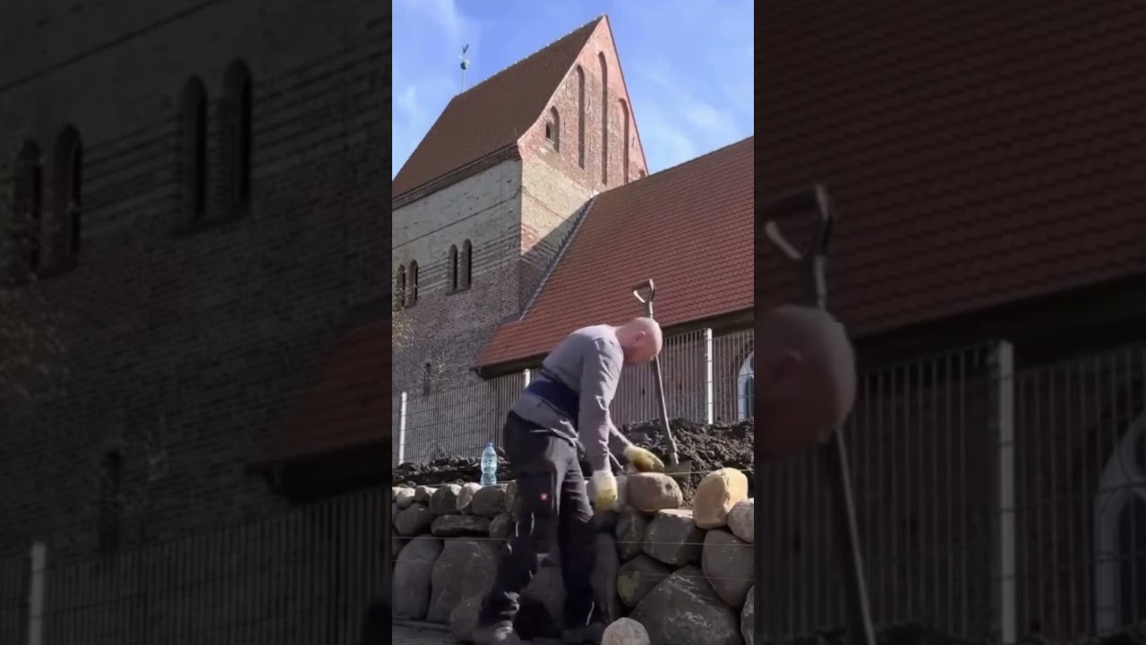 the process of laying stones to make a fence in the yard of the house 