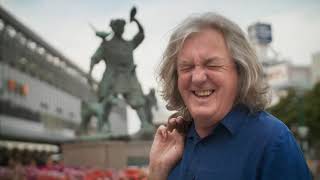 james may laughs at a statue