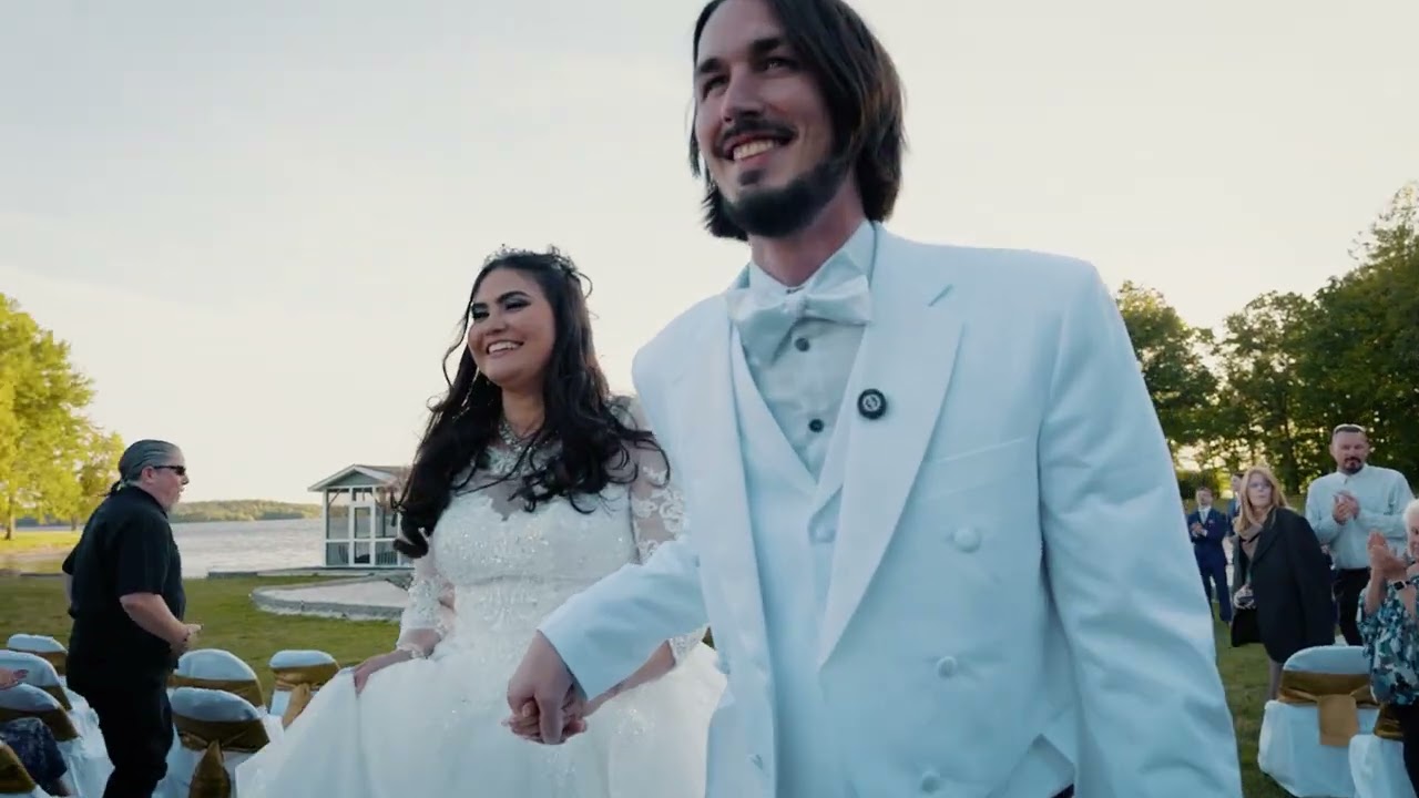Zachery y Daniela caminando juntos al atardecer el día de su boda, junto al lago