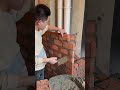 the process of installing red bricks to make a partition wall to cover large pipes in the room
