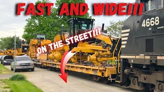 Wide load doesn't slow down as it rolls through a neighborhood! Parked cars on both sides of street!