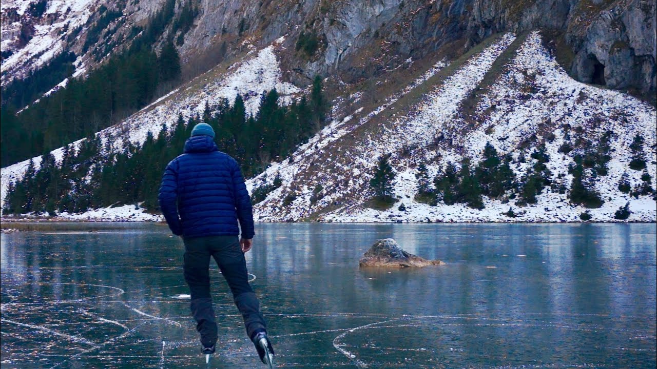 lonely ice skating on a black frozen mountain lake / slow tv nature