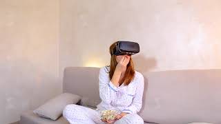 Woman watches video in VR glasses, sitting on couch in bright bedroom in evening screenshot 3