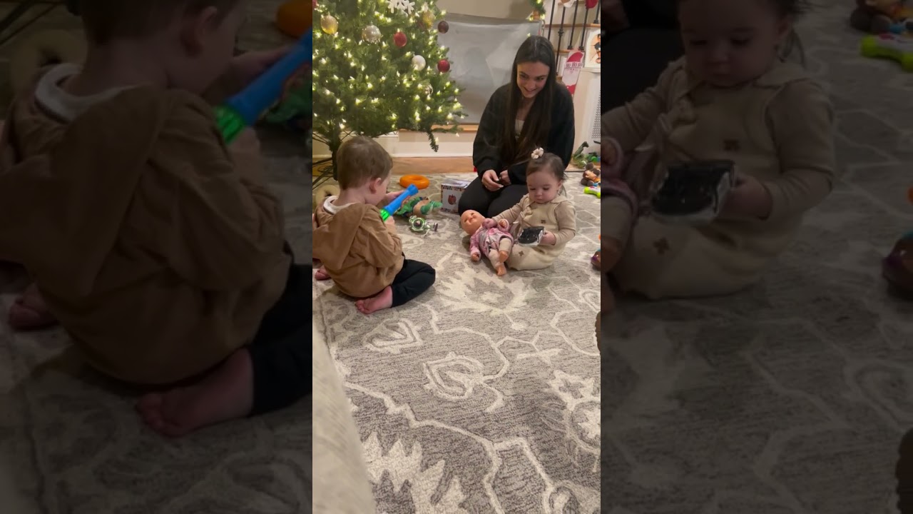 Boy throws Coco Melon toy at girl but woman catches it then he throws it again near Christmas tree