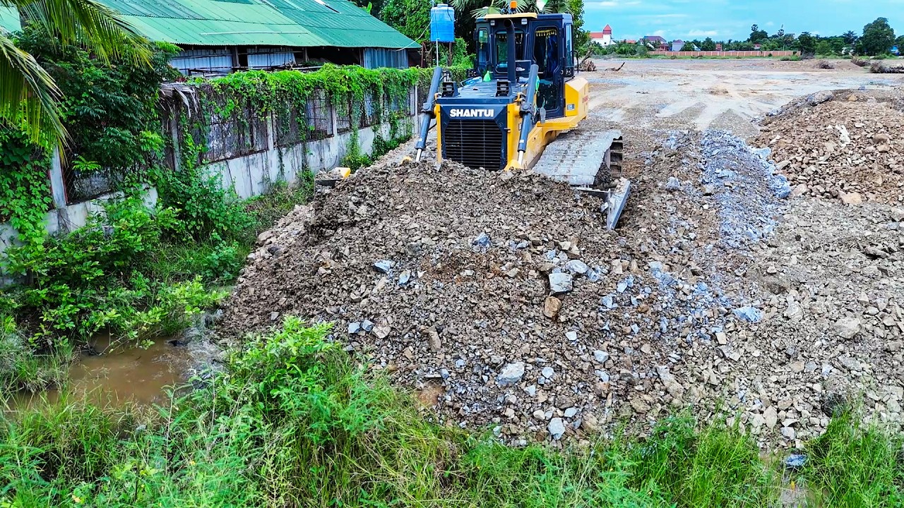 Nice & strong bulldozer pushing filling land with soil and dump trucks 