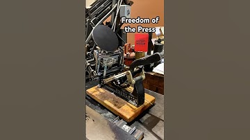 Using a tabletop printing press to print a phrase about having the freedom of the press