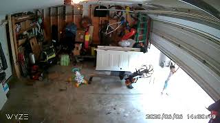 Boy hangs onto garage door as it goes up then he let's go and lands on ground (Security camera)