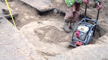 Compacting sand in trench prior to stone addition