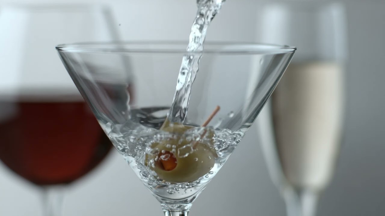 LIQUID BEING POURED OVER AN OLIVE IN A MARTINI GLASS EXTREME SLOW MOTION 4K