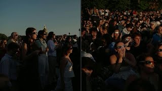 Parisians and visitors at the Invalides watch the eclipse as it reaches its peak in Paris | AFP